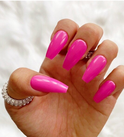 Bright pink almond-shaped summer nails with a glossy finish, accented by a sparkly silver ring on the ring finger.