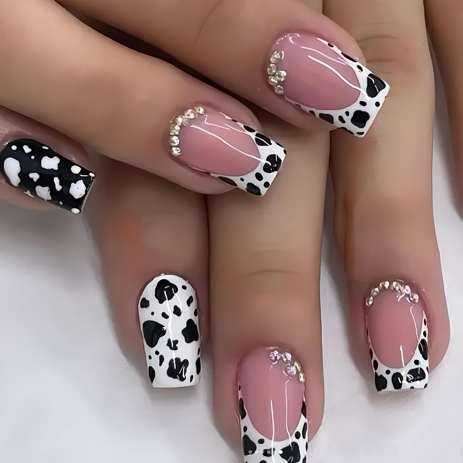 Bold cow print nail art paired with bright punchy pink polish for a playful summer look.

